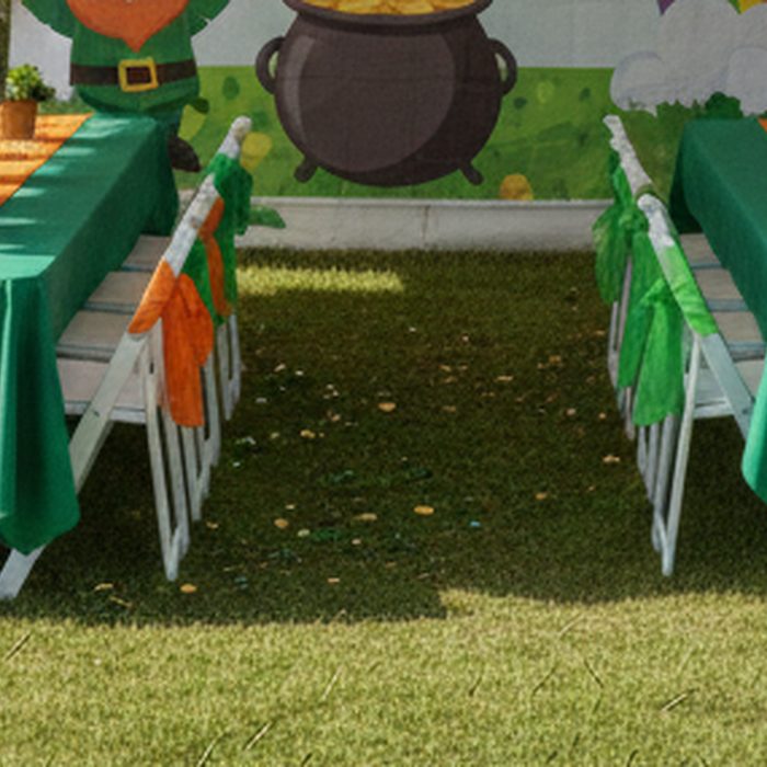 A banquet table covered in a green tablecloth with a contrasting orange table runner.